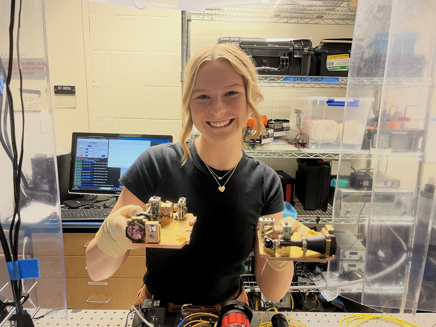 Abiagil in an optical lab holding two optical benches for the MIT CLICK research project.